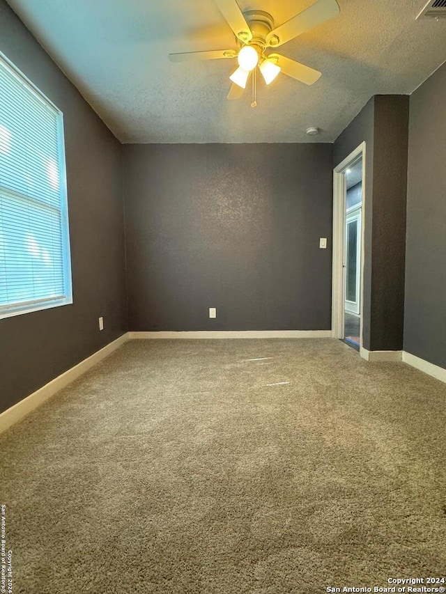 carpeted spare room with a textured ceiling and ceiling fan