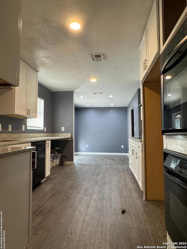 kitchen featuring dark hardwood / wood-style flooring, a textured ceiling, white cabinetry, and black appliances