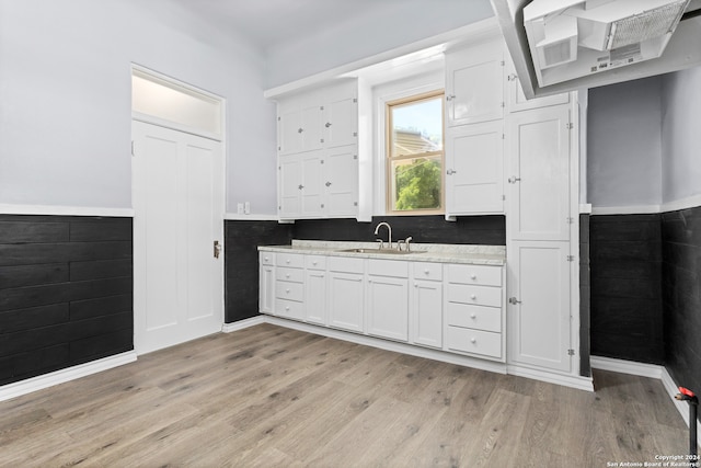 kitchen featuring white cabinets, light wood-type flooring, sink, and tile walls