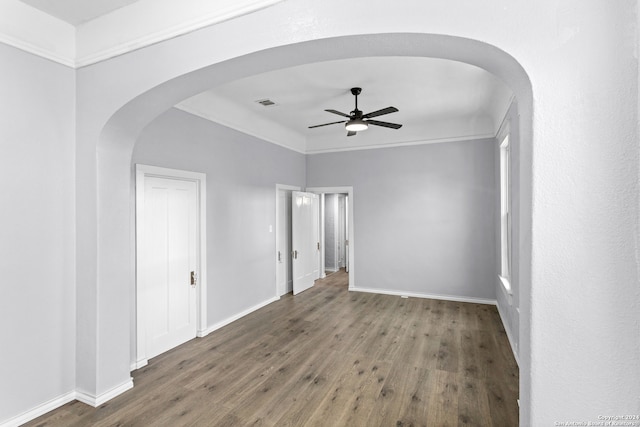 empty room featuring ceiling fan, crown molding, and dark wood-type flooring