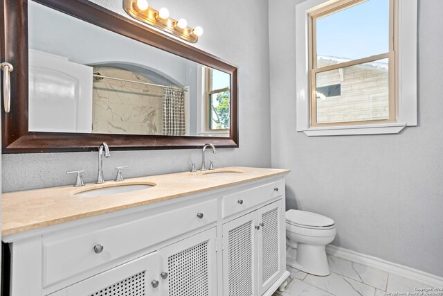 bathroom featuring a wealth of natural light, toilet, vanity, and walk in shower