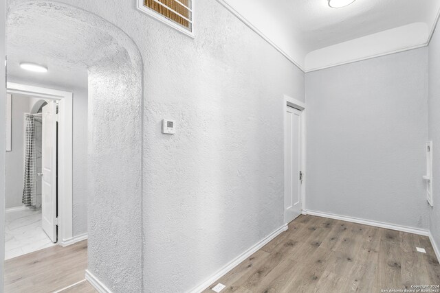 corridor with wood-type flooring and a textured ceiling