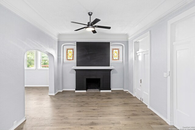 unfurnished living room featuring ceiling fan, a fireplace, wood-type flooring, and ornamental molding