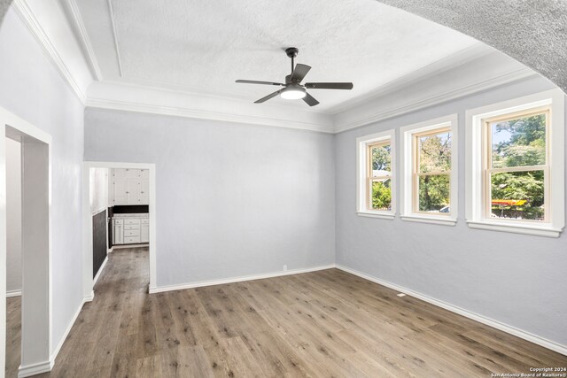 empty room with hardwood / wood-style floors, ceiling fan, ornamental molding, and a textured ceiling