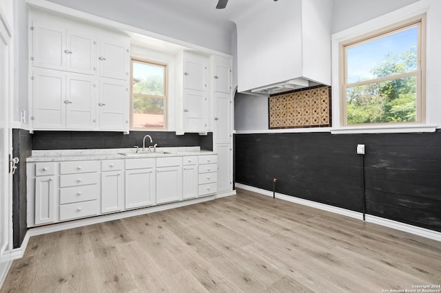 kitchen with white cabinets, decorative backsplash, light wood-type flooring, and sink