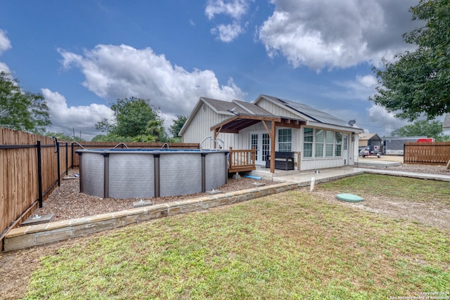 rear view of house featuring a lawn and a fenced in pool