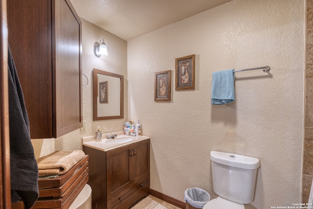 bathroom with a textured ceiling, toilet, and vanity with extensive cabinet space