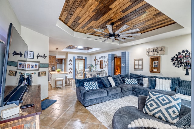 living room with wood ceiling, ceiling fan, light tile floors, and a raised ceiling