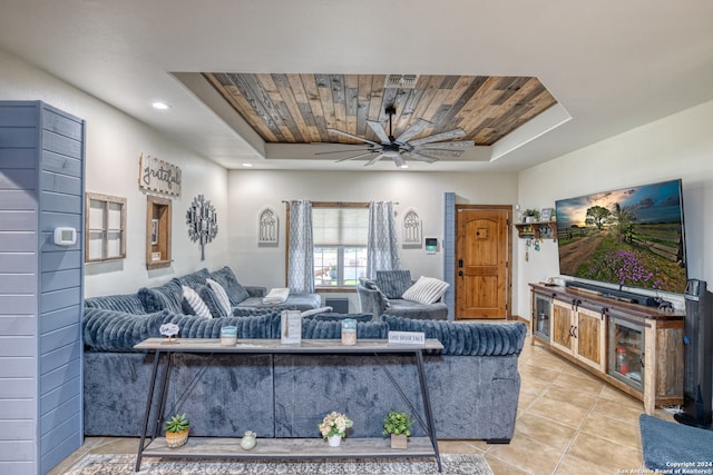 living room with a tray ceiling, ceiling fan, wooden ceiling, and tile floors