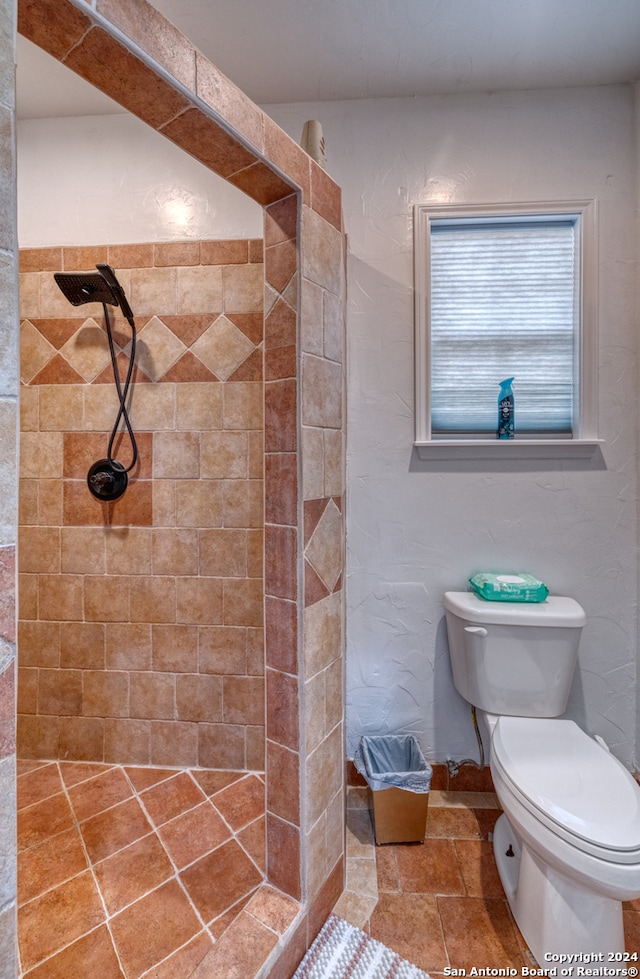 bathroom featuring a tile shower, tile flooring, and toilet