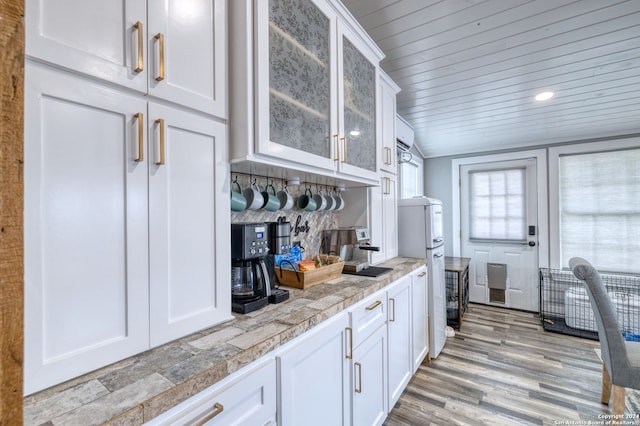 kitchen featuring white cabinets, wood-type flooring, and vaulted ceiling