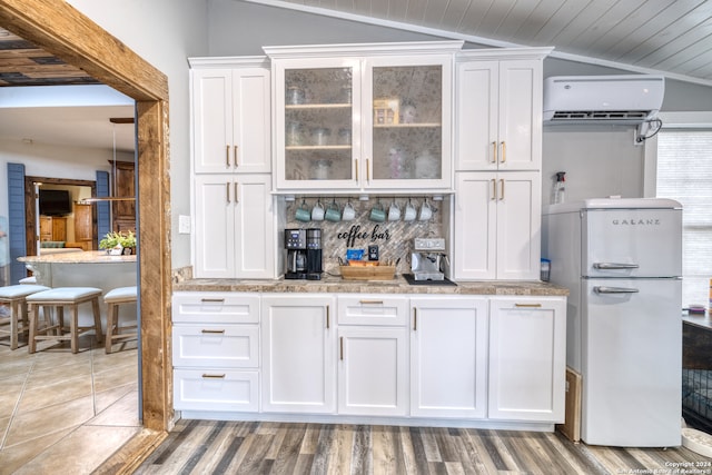 bar featuring vaulted ceiling, white cabinets, and white fridge