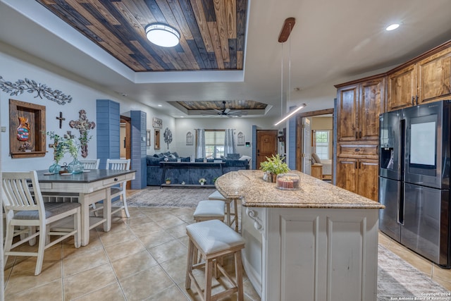 kitchen featuring ceiling fan, a tray ceiling, a healthy amount of sunlight, and black fridge with ice dispenser