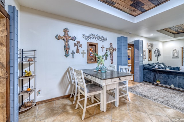 dining area with tile flooring, a raised ceiling, and wood ceiling