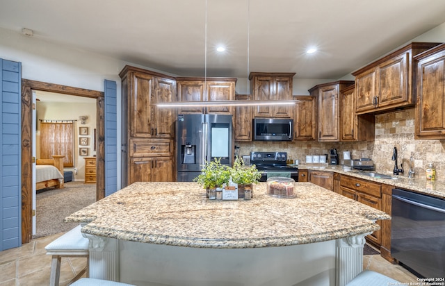 kitchen with light stone countertops, a kitchen island, appliances with stainless steel finishes, sink, and tasteful backsplash