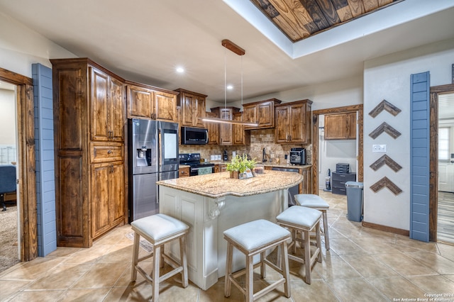 kitchen featuring tasteful backsplash, stainless steel appliances, light stone counters, a kitchen island, and a breakfast bar area