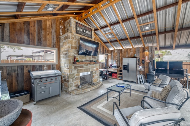 living room featuring a stone fireplace, vaulted ceiling, and wood walls