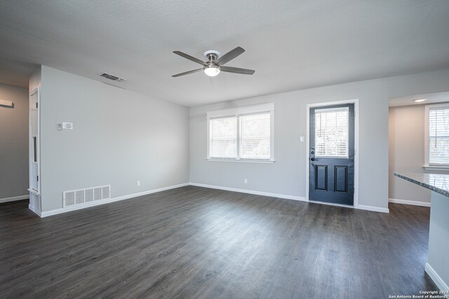 unfurnished living room with a wealth of natural light, ceiling fan, and dark hardwood / wood-style floors