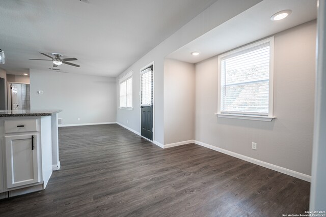 unfurnished living room featuring dark wood-type flooring and ceiling fan