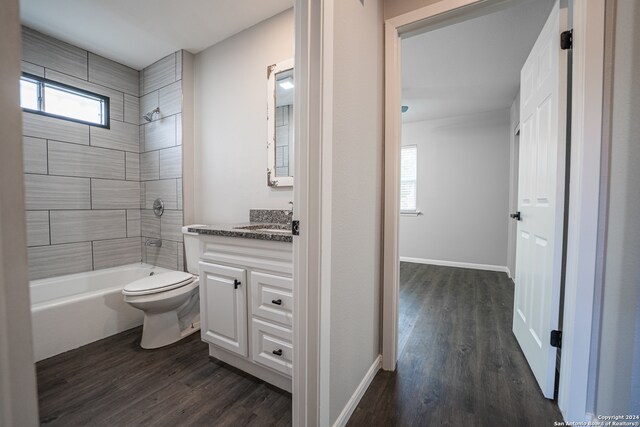 full bathroom with tiled shower / bath, hardwood / wood-style floors, toilet, and vanity