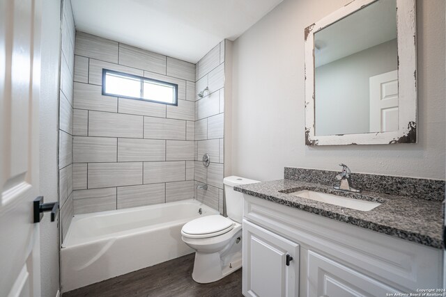 full bathroom featuring toilet, wood-type flooring, vanity, and tiled shower / bath