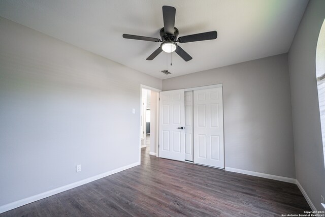 unfurnished bedroom featuring dark hardwood / wood-style flooring, a closet, and ceiling fan