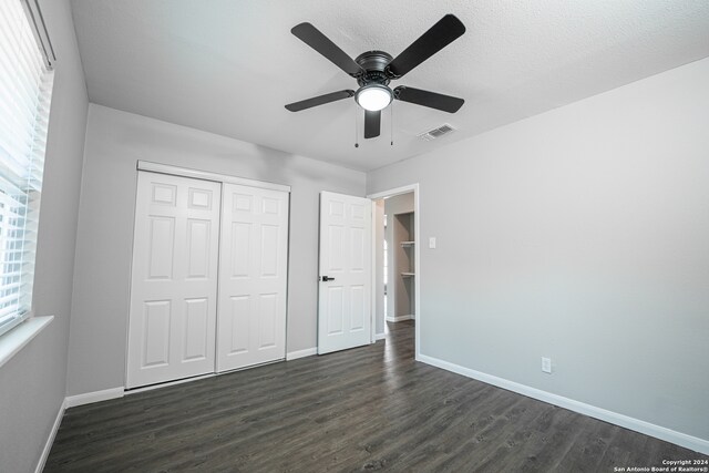 unfurnished bedroom featuring dark wood-type flooring, a closet, and ceiling fan