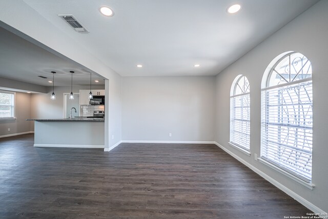 unfurnished living room featuring dark wood-type flooring and sink