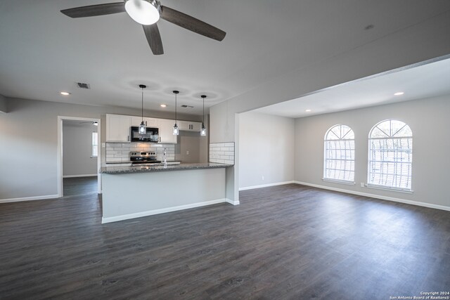 kitchen with ceiling fan, tasteful backsplash, stainless steel range, white cabinetry, and dark wood-type flooring