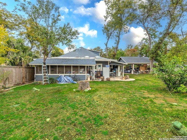 back of property featuring a lawn, a patio area, and a sunroom