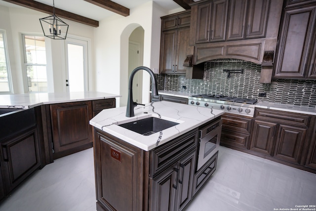 kitchen featuring pendant lighting, a kitchen island with sink, sink, decorative backsplash, and appliances with stainless steel finishes