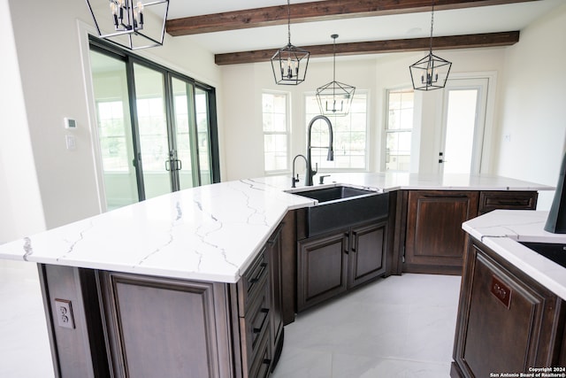 kitchen with french doors, sink, beamed ceiling, an island with sink, and decorative light fixtures