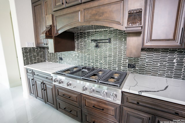 kitchen featuring dark brown cabinetry, tasteful backsplash, light stone counters, and stainless steel gas stovetop