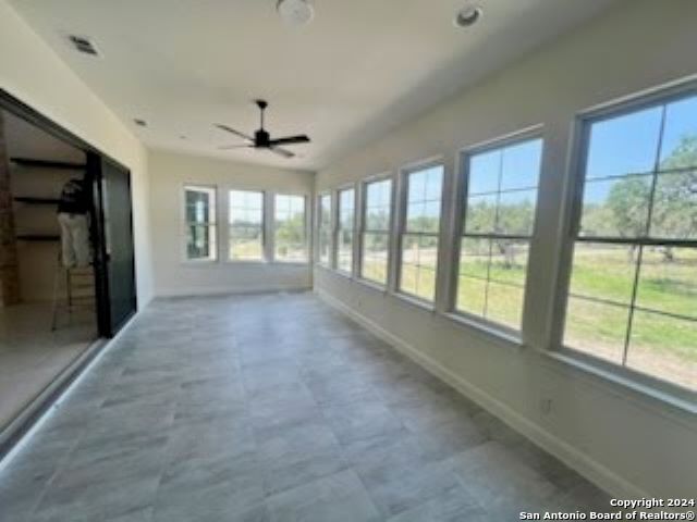 unfurnished sunroom with ceiling fan