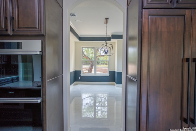 interior space featuring dark brown cabinets, pendant lighting, paneled fridge, and ornamental molding