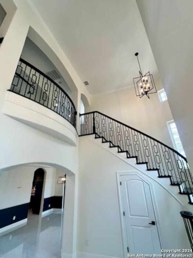 stairs with a chandelier and a towering ceiling