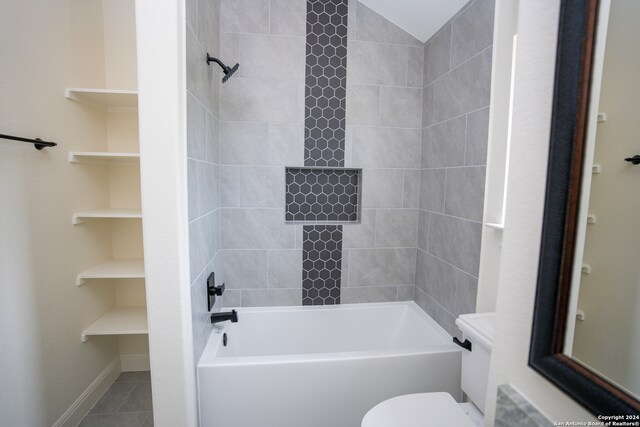 bathroom featuring tile patterned flooring, tiled shower / bath combo, and toilet