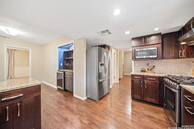 kitchen featuring light stone countertops, wine cooler, stainless steel appliances, wood-type flooring, and backsplash