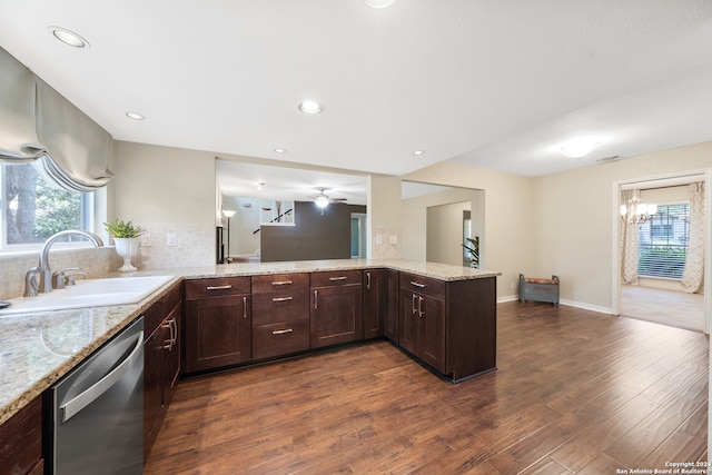 kitchen with ceiling fan with notable chandelier, kitchen peninsula, tasteful backsplash, stainless steel dishwasher, and sink