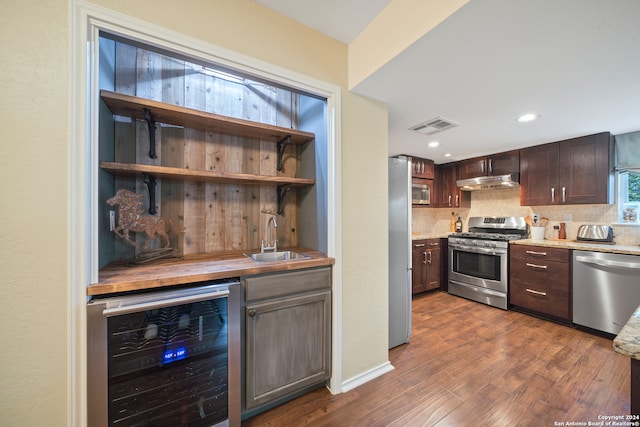 kitchen with dark brown cabinetry, dark hardwood / wood-style flooring, beverage cooler, appliances with stainless steel finishes, and sink