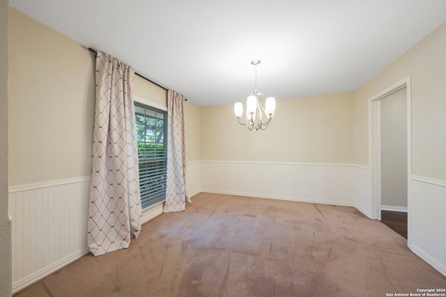 empty room featuring a notable chandelier and carpet flooring