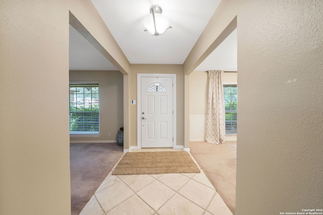 foyer entrance with a healthy amount of sunlight and light colored carpet