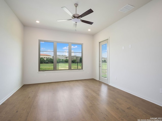 empty room featuring a healthy amount of sunlight, hardwood / wood-style flooring, and ceiling fan