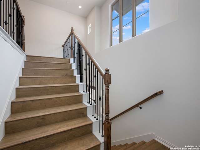 stairs with a towering ceiling and wood-type flooring