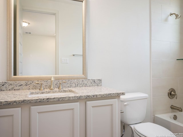 full bathroom with tiled shower / bath, vanity, and toilet