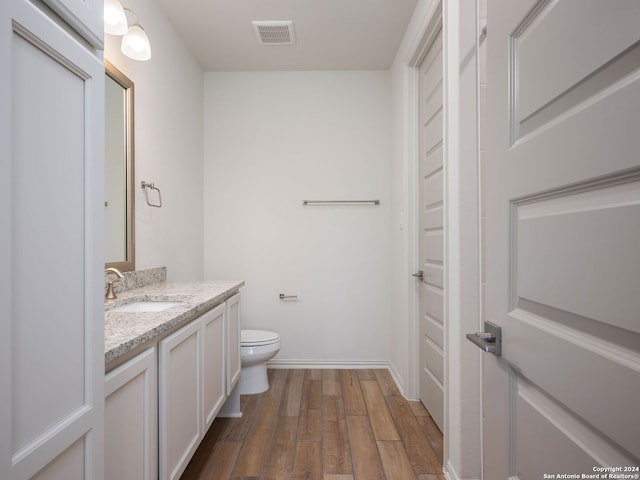 bathroom with vanity, toilet, and hardwood / wood-style flooring