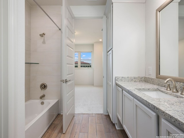 bathroom with tiled shower / bath, hardwood / wood-style flooring, and vanity