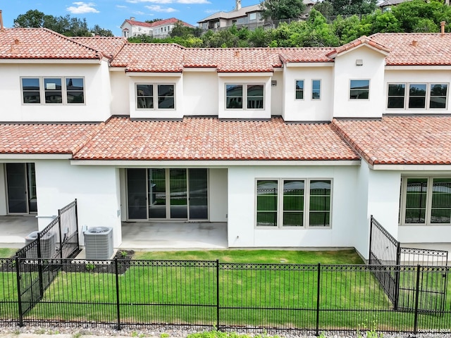 back of house featuring central air condition unit and a lawn