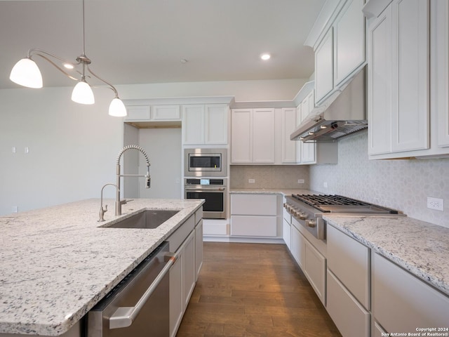 kitchen with hanging light fixtures, dark wood-type flooring, stainless steel appliances, backsplash, and sink