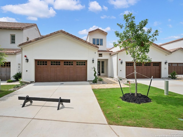 mediterranean / spanish home with a garage and a front lawn